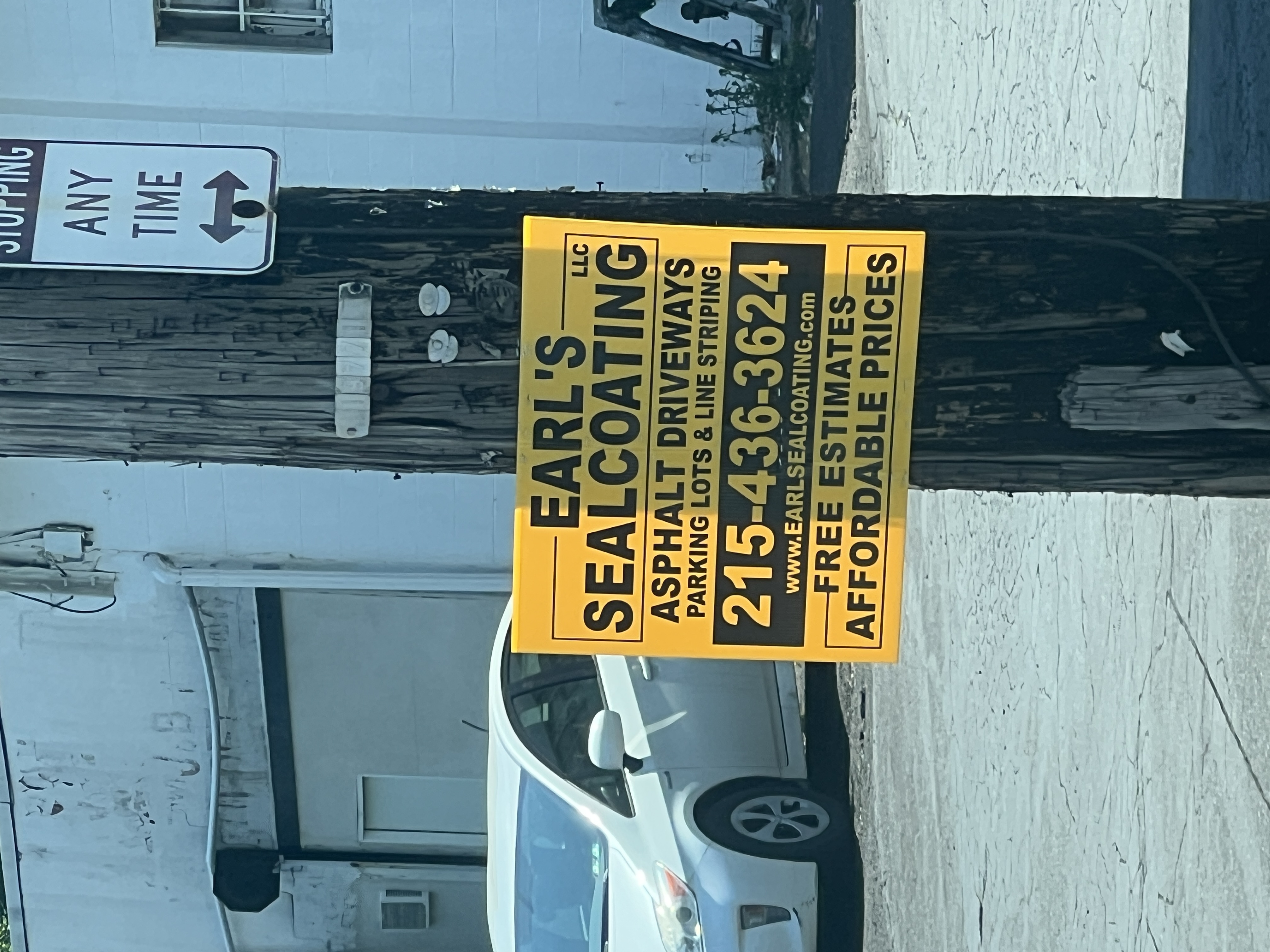 Yard sign for Earl's Sealcoating LLC — yellow background, black text, asphalt driveways / parking lots / line striping, 215-436-3624, www.earlsealcoating.com.