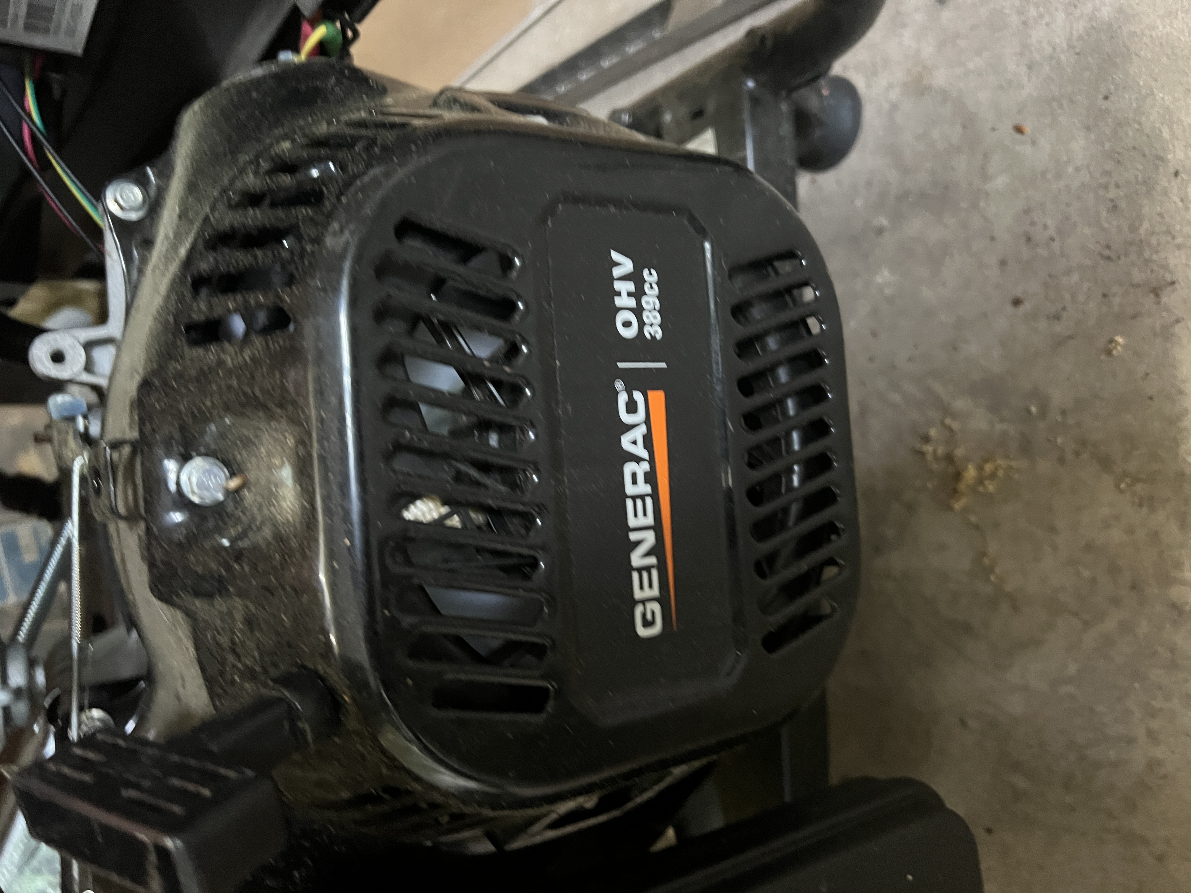 Husqvarna ST 324 two-stage snow blower in the New Hope garage. Orange housing with the ST 324 model number visible on the side panel, Husqvarna logo on the dashboard, aftermarket LED work light mounted on the handlebars.
