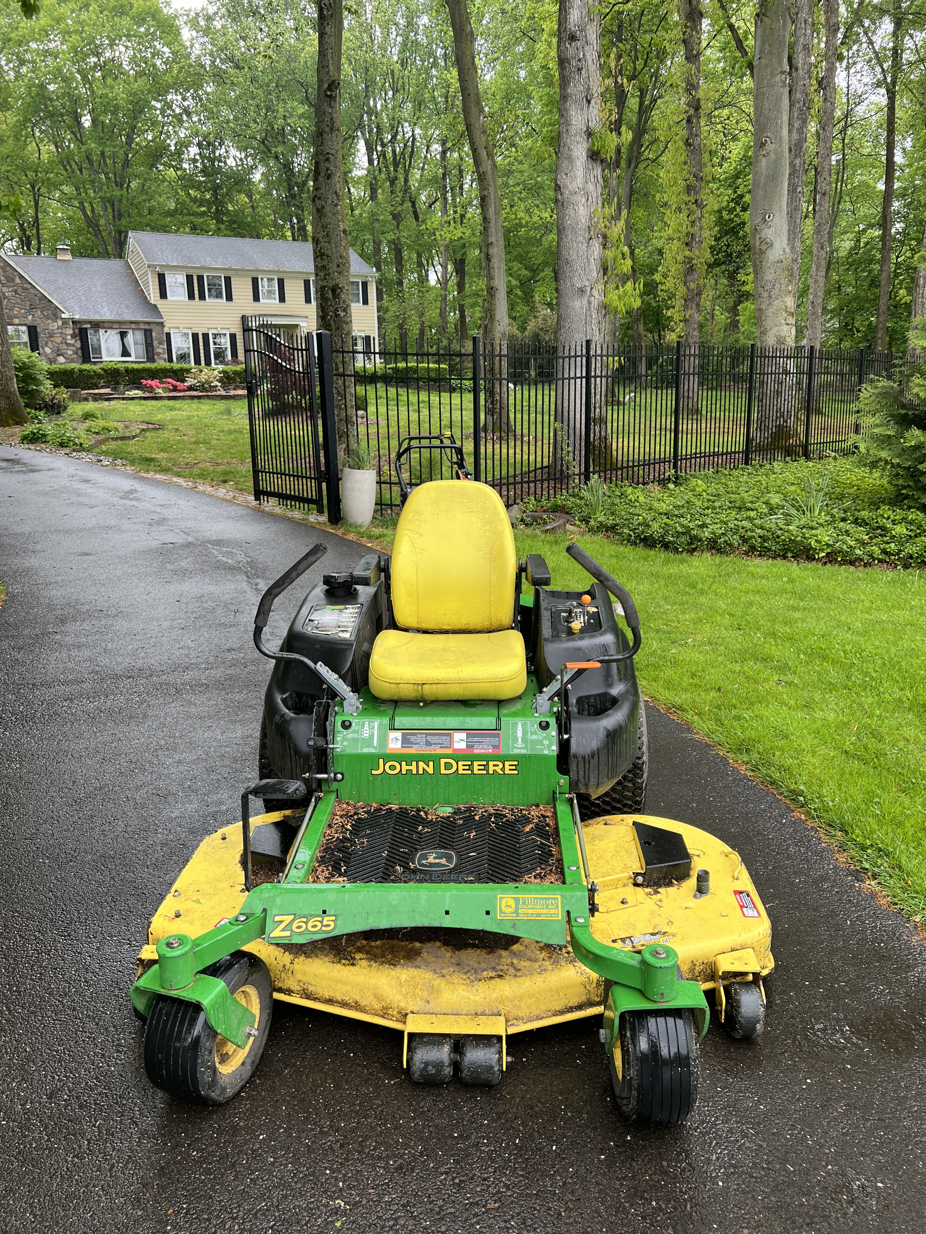 John Deere Z665 EZtrak zero-turn mower on the driveway at New Hope — yellow seat, green deck, Z665 model badge.