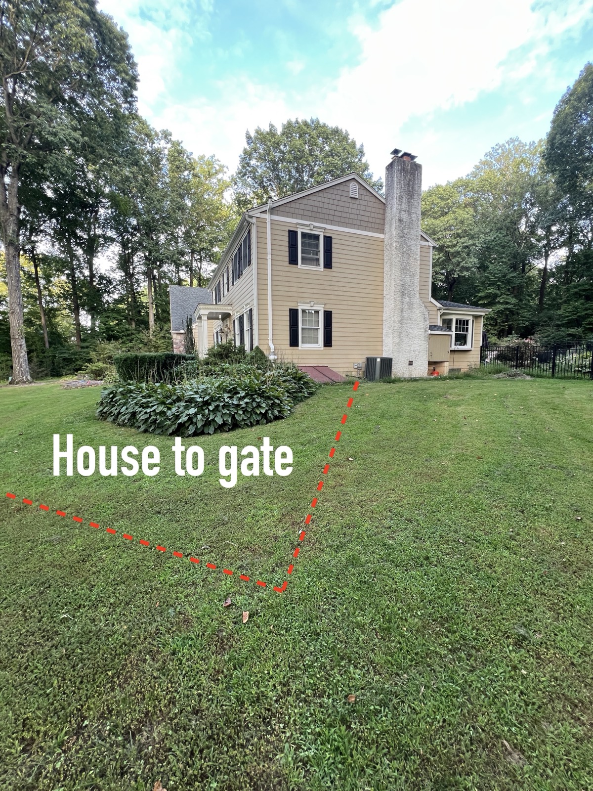 Colonial house with the AC condenser at the base, a red dashed line leaving the back corner and running down-left across the front lawn, labelled House to gate.