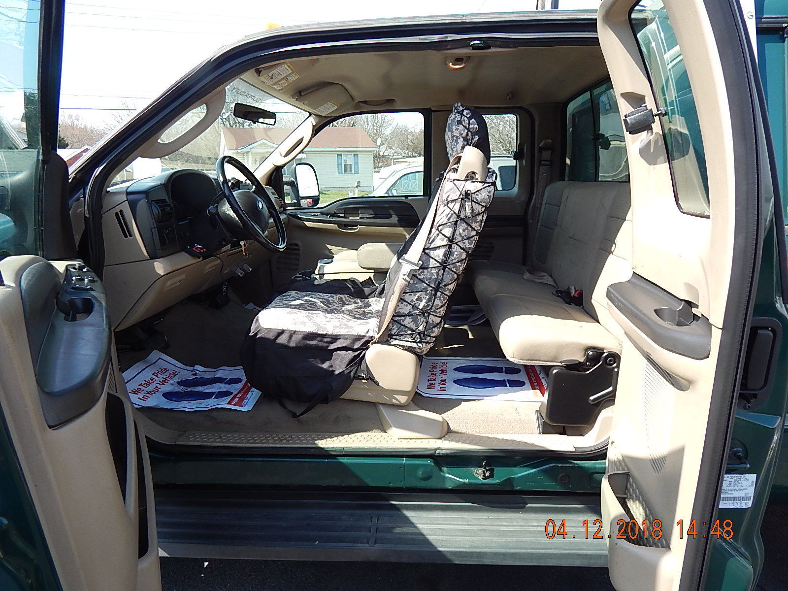 2018-04 eBay listing photo: interior driver/passenger area showing tan cloth seats with digital-camo seat cover