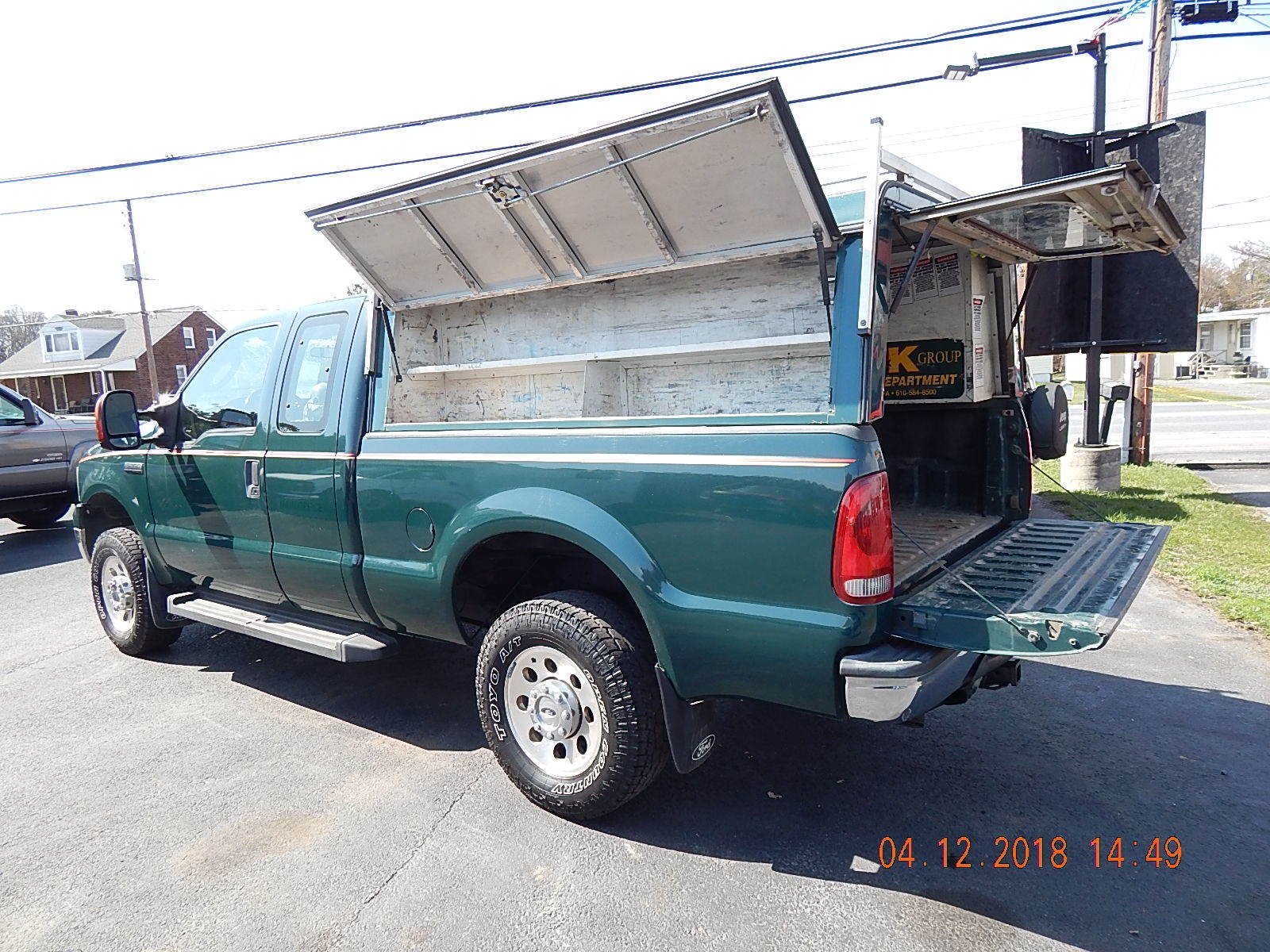 2018-04 eBay listing photo: rear-quarter showing ARE aluminum utility topper with side access door + ladder rack